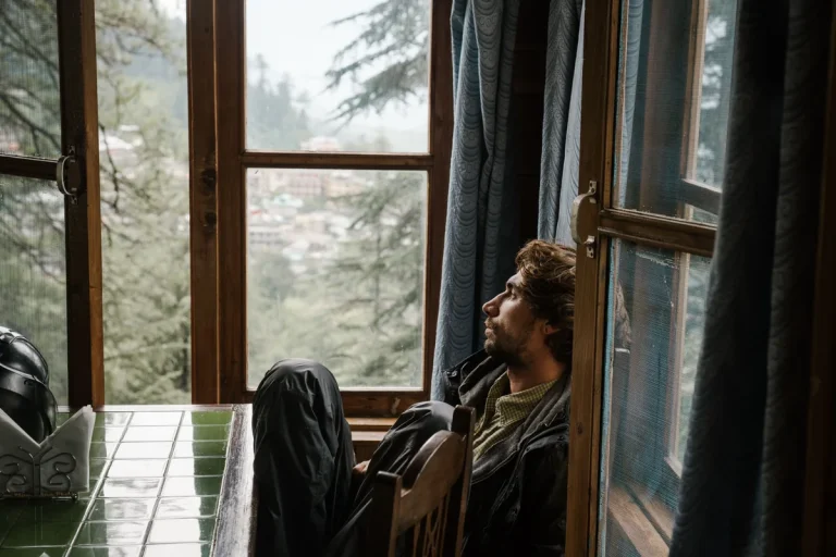 Person sitting by a window on a grey day, reflecting the difference between sadness and depression
